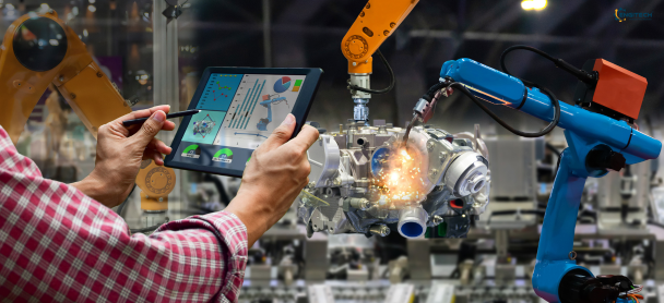 Engineer monitoring and controlling a robotic assembly process using a digital tablet while industrial robots operate on a production line