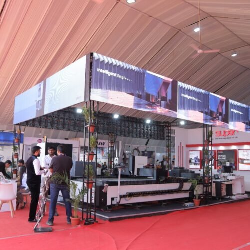 Industrial exhibition stall showcasing advanced manufacturing machinery with visitors interacting at a modern expo setup under a dome pavilion